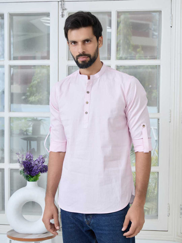 A man wearing a pink solid cotton short kurta with mandarin collar and long sleeves.